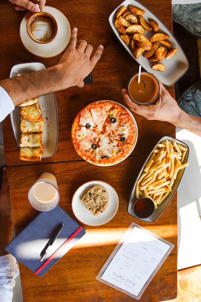 Aesthetic flatlay of Coffee Network table: coffee, pizza, fries, and notebook